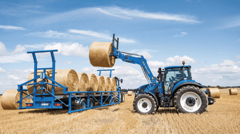 Ag Tractor stacking large hay bales onto a trailer