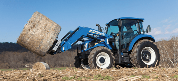 Tractor moving large hay bale