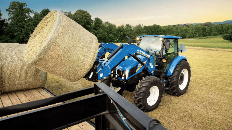 Man using Compact Tractor to load hay bales onto back of trailer